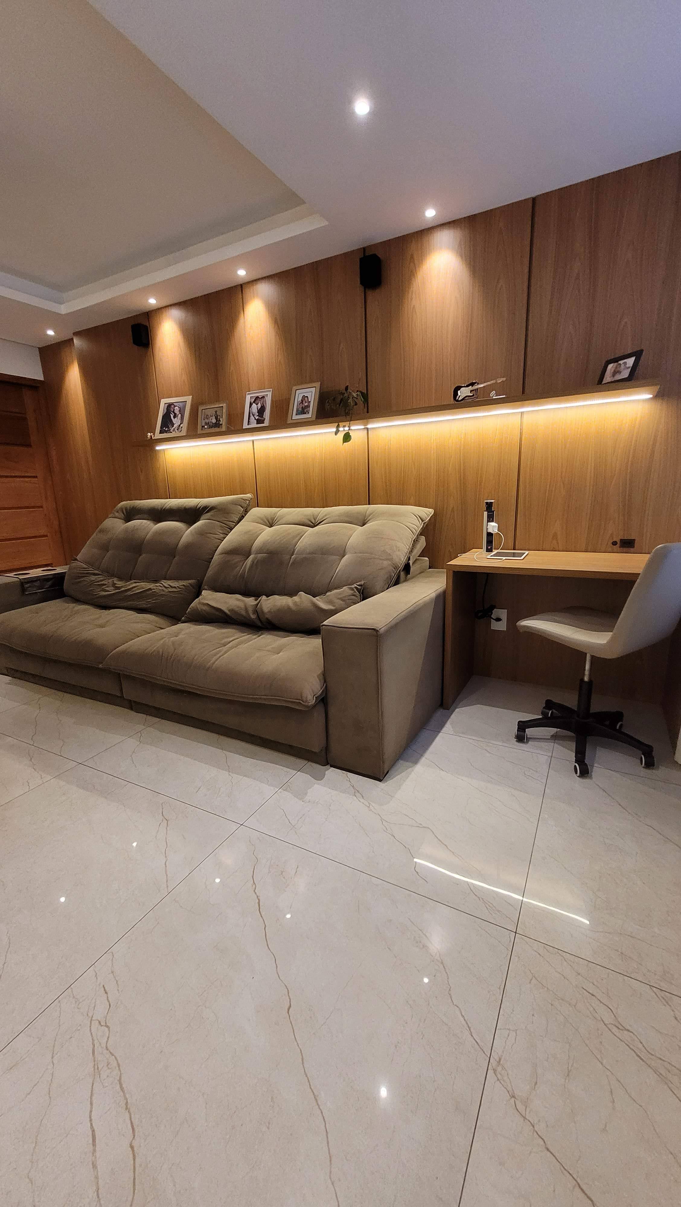 Sala planejada acolhedora com painel em madeira e iluminação quente